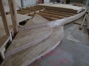 Curved wooden platform framing with exposed joists and partially installed plywood decking under construction.