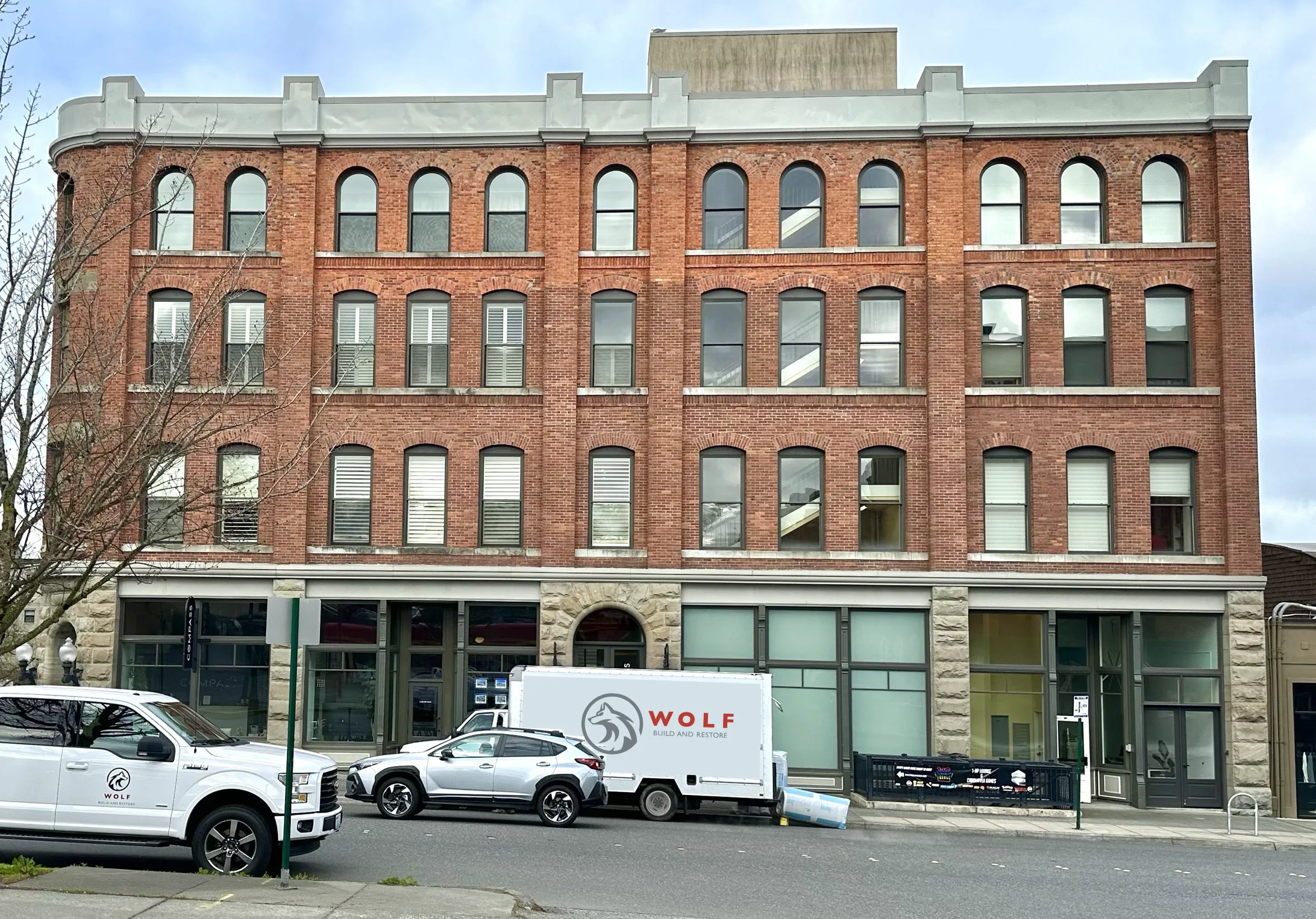 Red-brick building with Wolf Build and Restore trucks outside, part of an insurance restoration project in Bellingham.